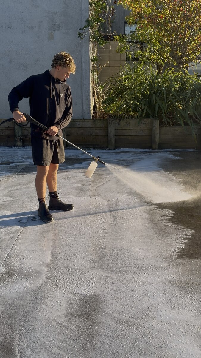 Commercial exterior cleaning, foam pre-treatment being applied to a large concrete forecourt